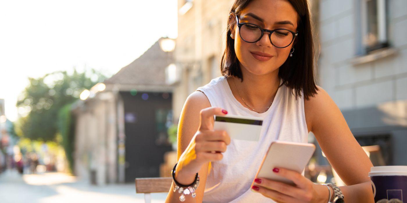 Girl looking at debit card while having coffee outside at cafe