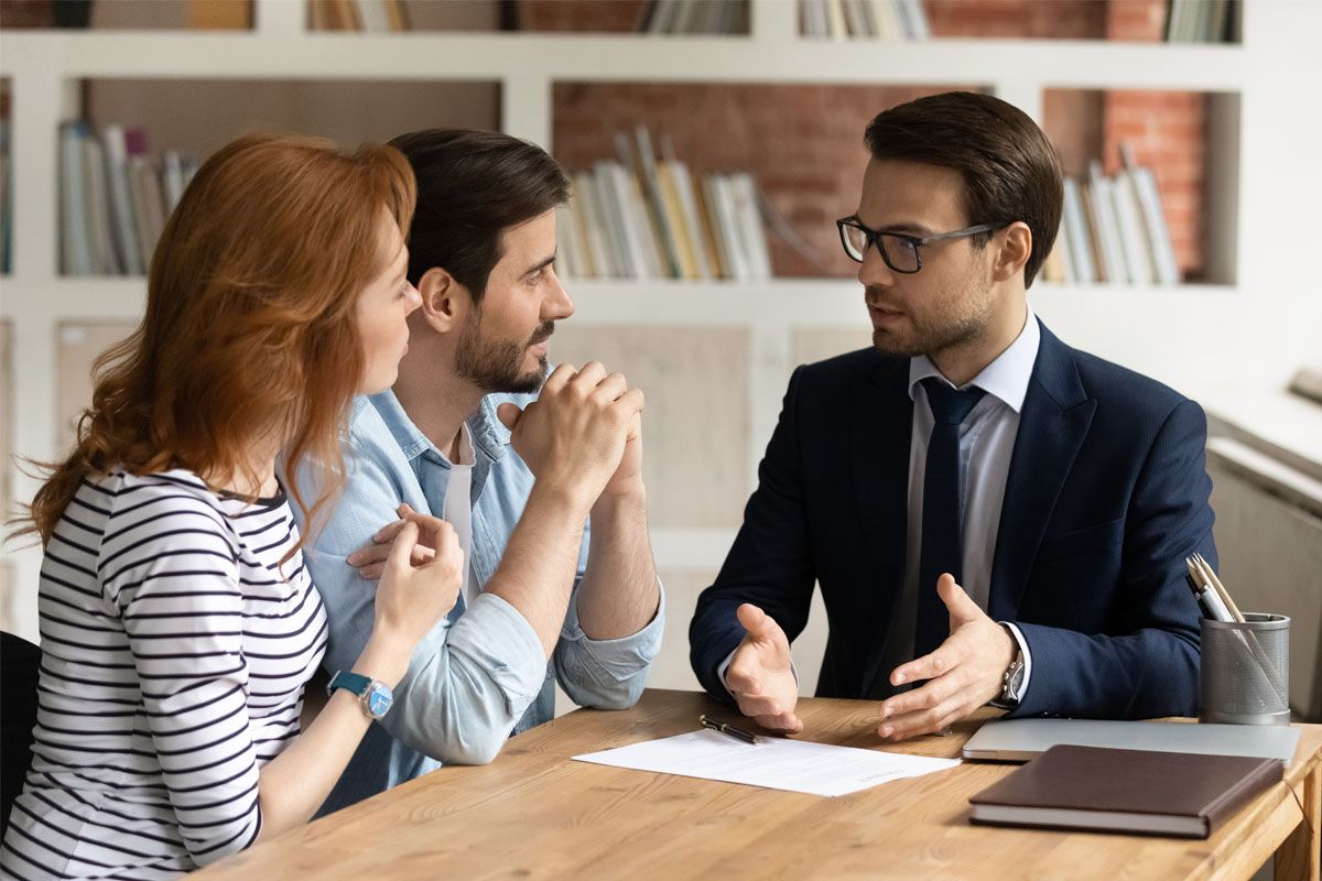 A couple discusses refinancing with their credit union mortgage loan advisor.