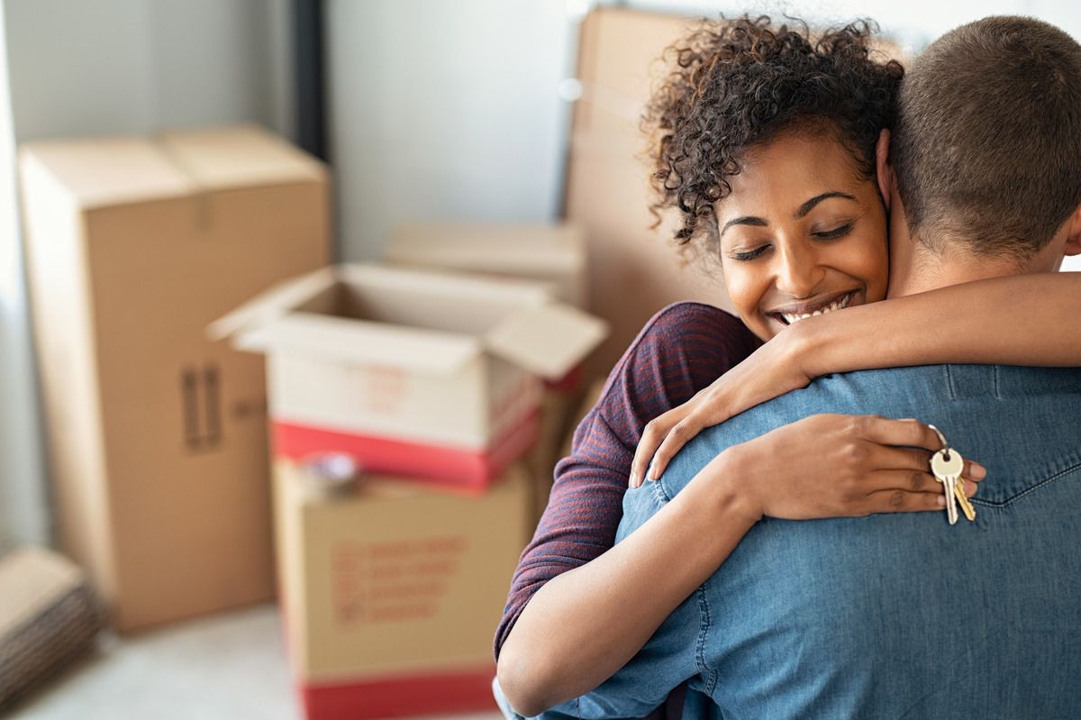 A woman hugs her husband after they move into the new home they purchased with a credit union mortgage loan.