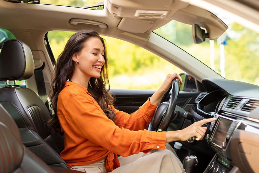 A happy woman plays the radio in her new car that she bought with a credit union auto loan.