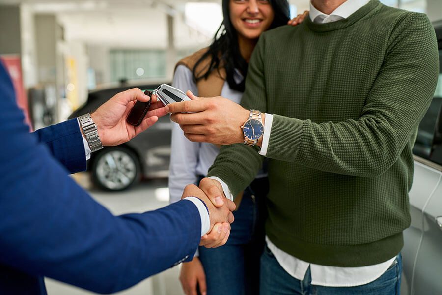 Couple being handed keys to their new car