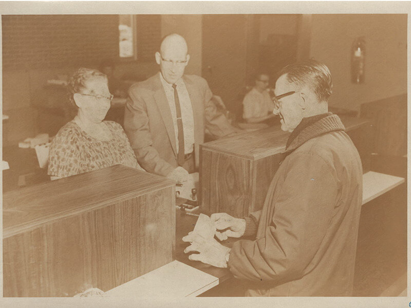 A CU member with tellers in the 1960's.
